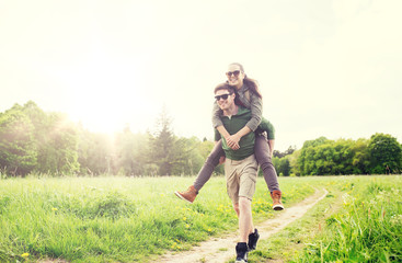 travel, hiking, backpacking, tourism and people concept - happy couple with backpacks having fun and walking along country road outdoors