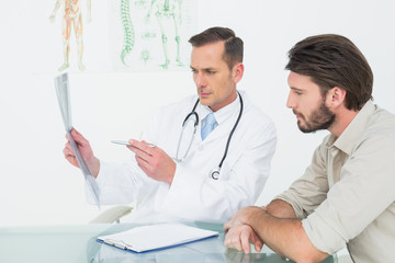 Male doctor explaining spine xray to patient