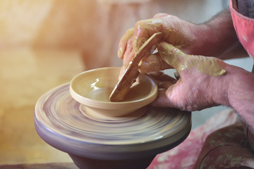 Creating a jar or vase of white clay close-up. Man hands, pottery, workshop, ceramics art concept. Twisted potter's wheel