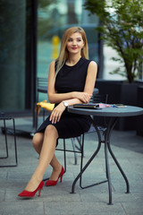 Beautiful girl sitting on the table and do her work, talk at phone, write mail