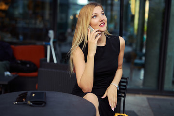 Beautiful girl sitting on the table and do her work, talk at phone, write mail