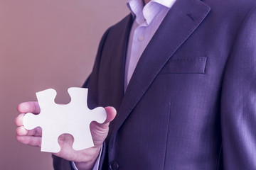 Jigsaw puzzle in man hand. Close up businessman Holding Puzzle Piece. Copy space.