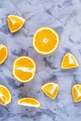 Sliced orange with various pieces on a gray background. Top view, flat lay