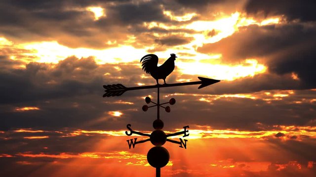 Weathervane cockerel floating against red sunset