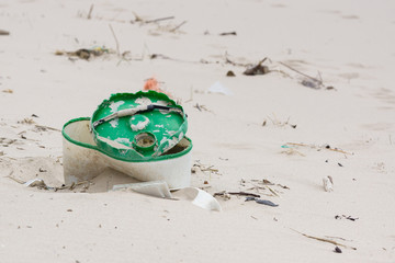 Plastic rubbish washed up on a beach and part buried in the sand an example of the many pieces of garbage in the sea around the world