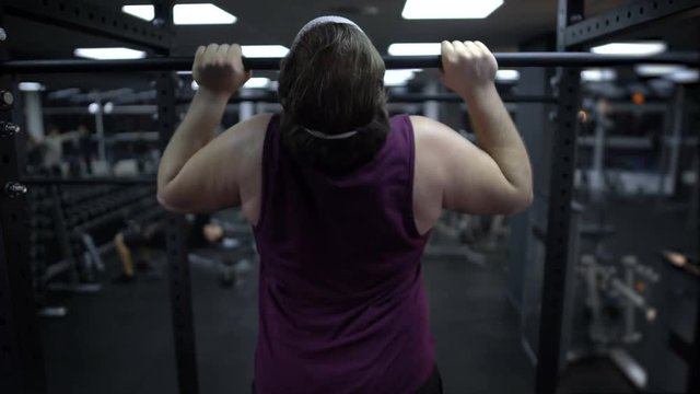 Man trying to pull up his heavy body, increase muscle strength, workout in gym