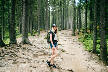 Obraz premium Young beautiful blonde babe portrait. Cute lovely female traveler with backpack hiking in mountains at nture on vacation. Tourist woman in camping trip. Walking up the hiils. Skinny stylish girl.