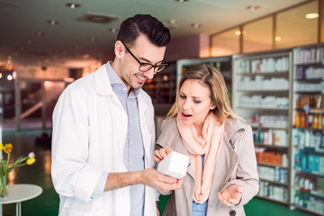 Male pharmacist serving a female customer.