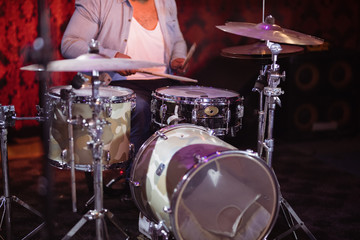 Fototapeta na wymiar Mid section of drummer performing on stage at nightclub