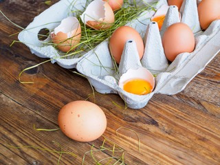 Ganze Eier und Eidotter in der Schale in einem Eierkarton auf einem braunen rustikalen Holztisch. Nahaufnahme, Eiweißprodukt.