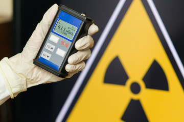 Radiation supervisor in glove with geiger counter checks the level of radiation - obrazy, fototapety, plakaty