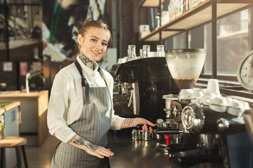 Tattooed barista making coffee in professional coffee machine