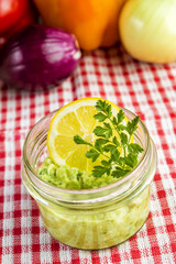 Mexican sauce guacamole in a jar with lemon slice and parsley