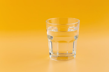 Pure water in a glass on an orange background