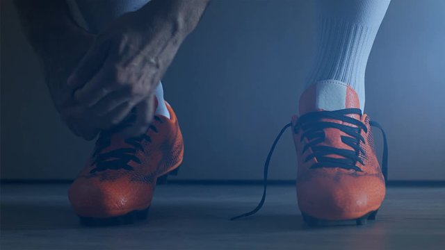 Soccer football player put on his shoes. 