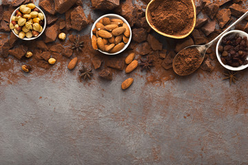 Crushed chocolate bar pieces and cocoa on gray background, top view