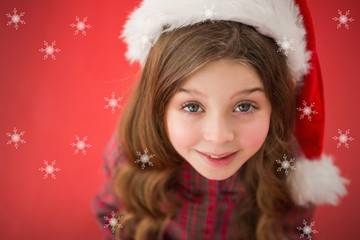 Happy little girl in santa hat  against snowflakes