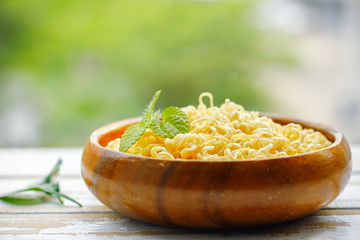 Noodles on Wooden bowl on Table with green background.