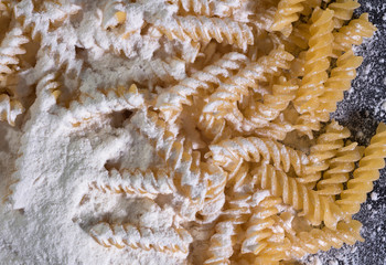 Yellow Italian pasta, spaghetti in flour against the black isolated background. A view from above.