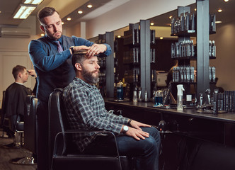 A stylish Master barber does a haircut to the client. Men's haircut in a barbershop.