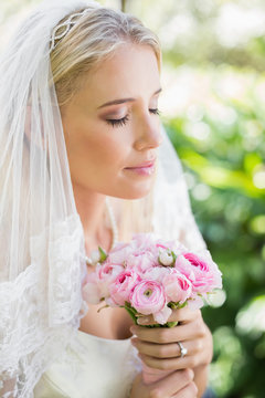 Content bride wearing veil holding bouquet with eyes closed