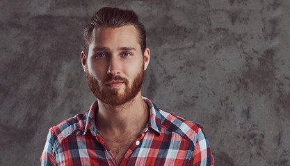 Young handsome redhead model man in a flannel shirt on a gray background.
