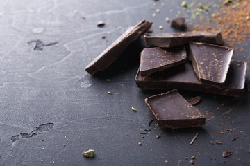 Dark chocolate pieces and cocoa powder over black background