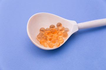 A wooden spoon with red caviar on a blue background. Orange balls, similar to caviar.