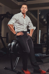 Fototapeta na wymiar Handsome confident businessman in formal clothes came to the gym for training after a hard day's work.