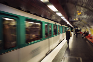 Blurry motion image of woman walking in a subway station. Train approaches. Lifestyle and culture...