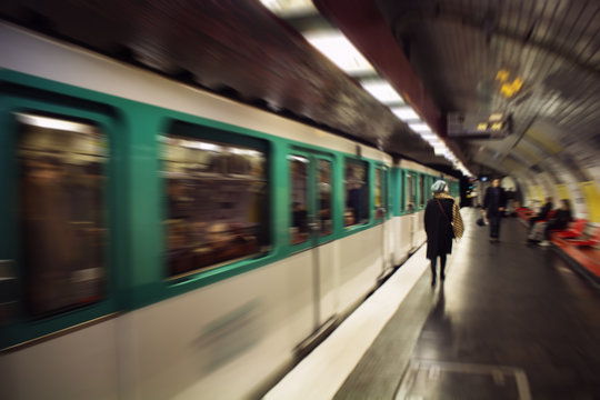 Blurry motion image of woman walking in a subway station. Train approaches. Lifestyle and culture concept
