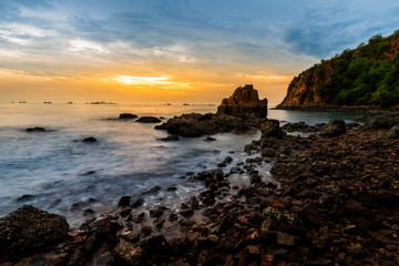 Sunset At rock beach in Conburi, Thailand. Very colorful sun light and smooth wave