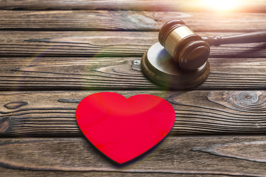 heart made of wood, hammer of a judge on a wooden background. family law, divorce. conflicts.