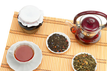Teapot, cup of tea, jam jar and tea leaves isolated on white background.