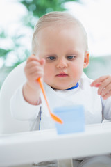 Baby looking at a plastic spoon while holding it