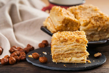 Slice of sweet classic layered cake Napoleon and hazelnuts 