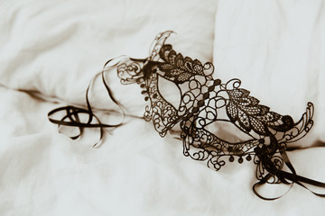 Black venetian mask on bed