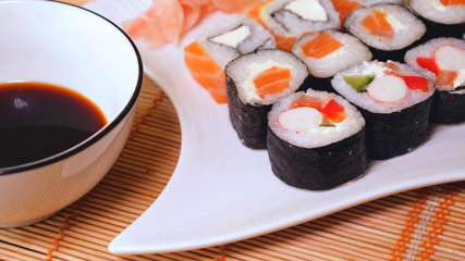 Fresh sushi, Philadelphia cheese, crab sticks, salmon, rice, ginger, soy, orange background, macro.