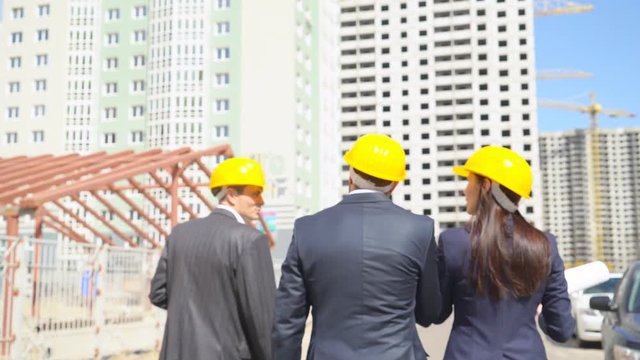 businessmen are going on construction and are considering a new project under construction. Serious people in suits in protective helmets of yellow color. 4k