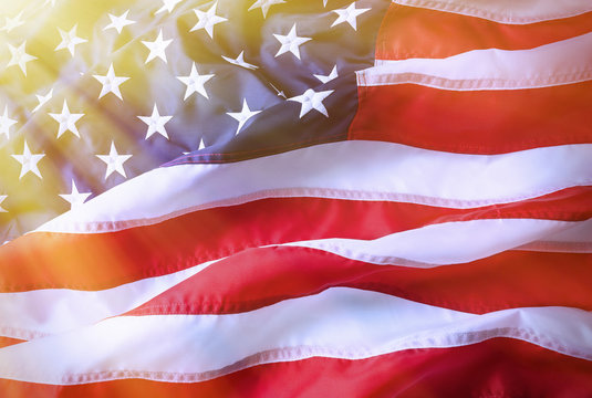 American flag background. Brightly lit American flag. Sunlight, sunflare on the right side.
