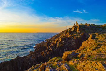 Picturesque seascape with lighthouse, cliffs, rocks and stacks in beautiful sunset