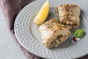 Baked Pollock fish with lemon and spices on a plate Napkin on the table
