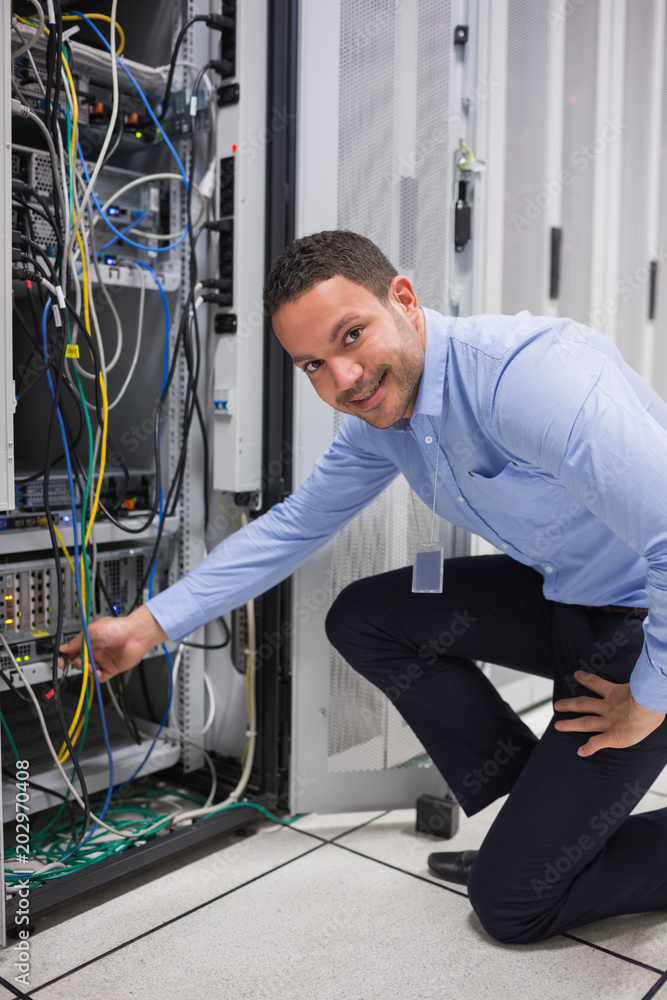 Poster smiling man adjusting cable in the server