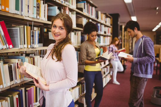 Happy student taking book from shelf