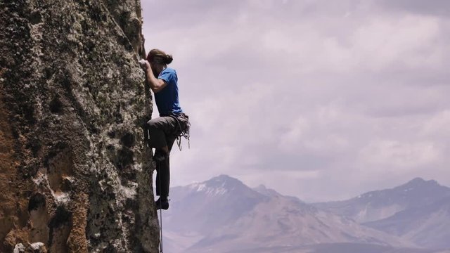 Man climbs a rock wall with an incredible panoramic view of the North Ridge of Park Huascaran, Peru. Slow motion