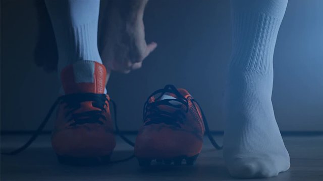 Soccer football player put on his shoes. Slow Motion. 