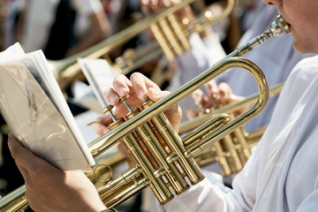 Closeup of a children's orchestra playing on musical wind instruments.