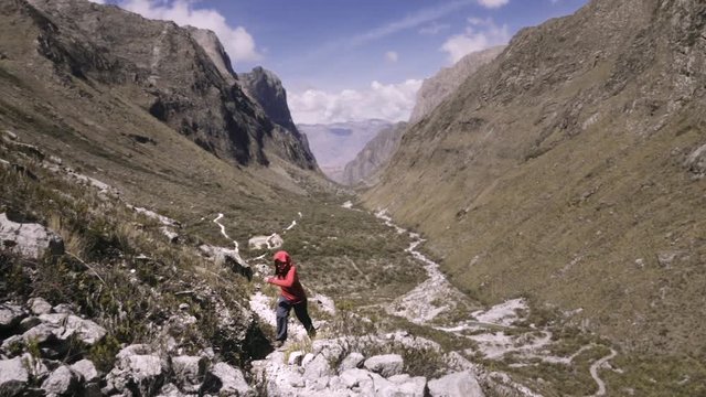 Person wearing a red hood escaping through a rocky path of the Huascaran National  Park. Slow motion