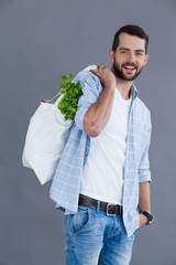 Man in light blue shirt carrying a grocery bag 