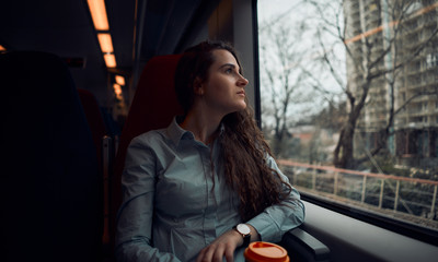 Thoughtful girl was going home on the train. Beautiful view from the train window.